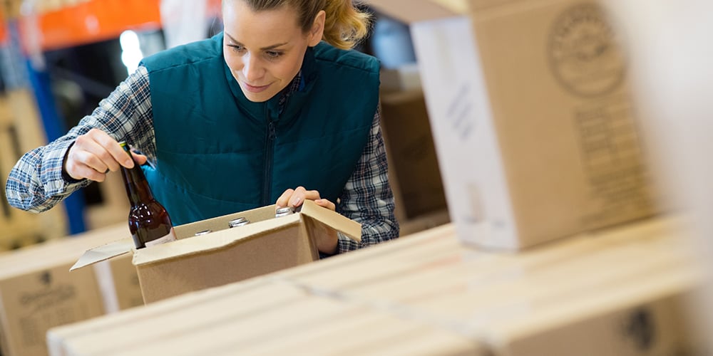 Warehouse worker inspecting a wine bottle before packaging in a distribution center