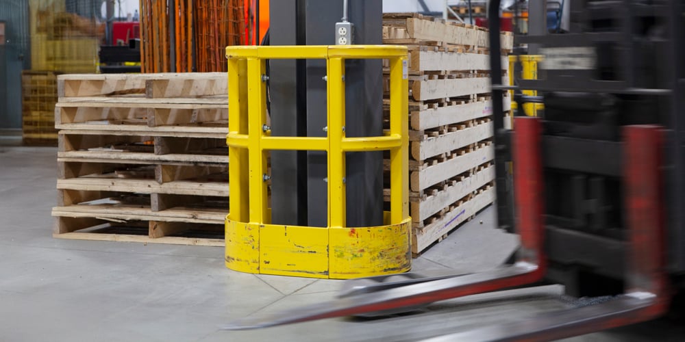 Warehouse aisle with pallet racking protected by guardrails and safety barriers, illustrating how racking protection prevents forklift damage and keeps workers safe.