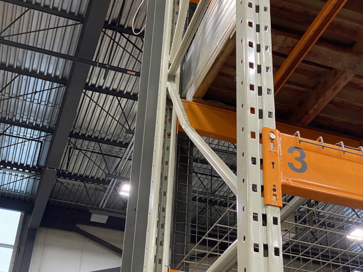 A severely dented diagonal brace on a warehouse rack