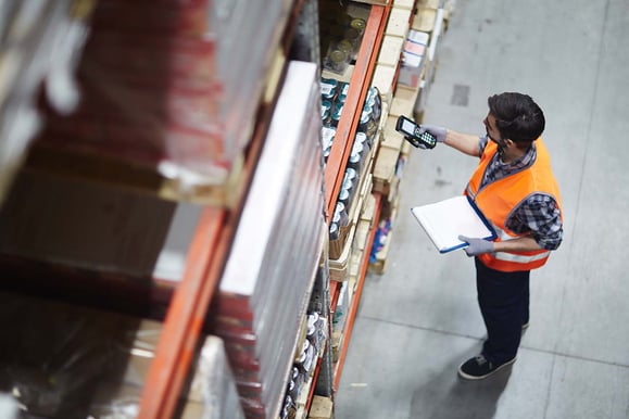 Un employé d'entrepôt numérise des articles sur un palletier