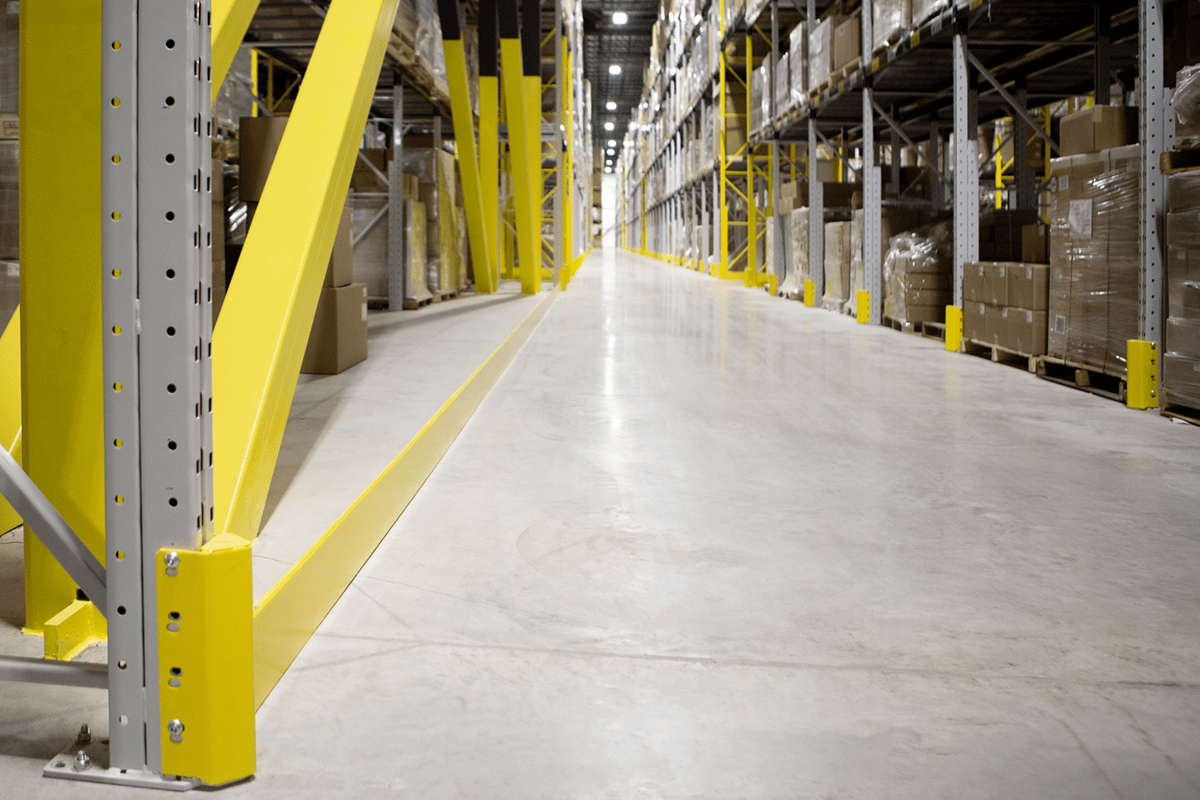 DAMO NOSE GUARD and DAMO PALLET STOPPER protecting a warehouse racking aisle.