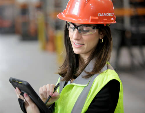 Un femme qui inspecte un palettier avec son ipad dans un entrepot