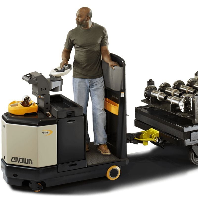 Electric tow tractor pulling carts through a warehouse