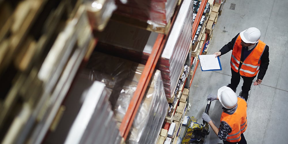 Two warehouse employees looking at pallet rack systems