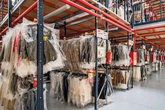 Hanging racks with dresses in garment warehouse