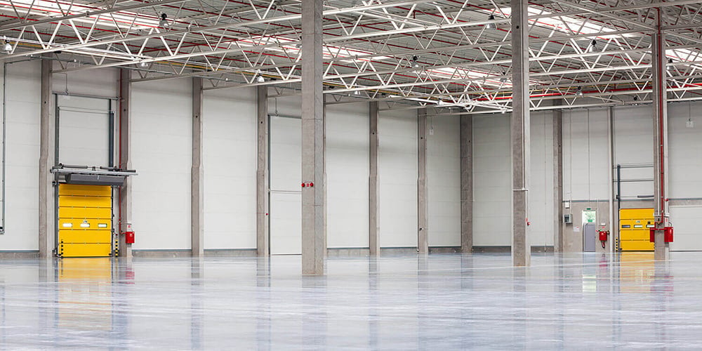 Structural building columns supporting the roof of an open warehouse, exposed to forklift traffic