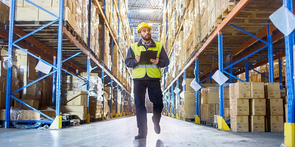 Warehouse worker walking in between aisles to assess pallet rack damage