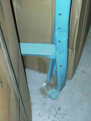 Damaged pallet rack upright with a twisted, buckled column