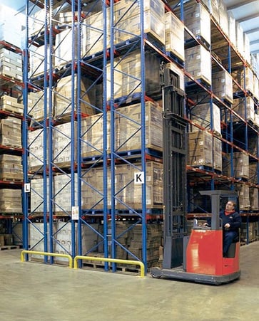 A forklift being operated in a warehouse. 