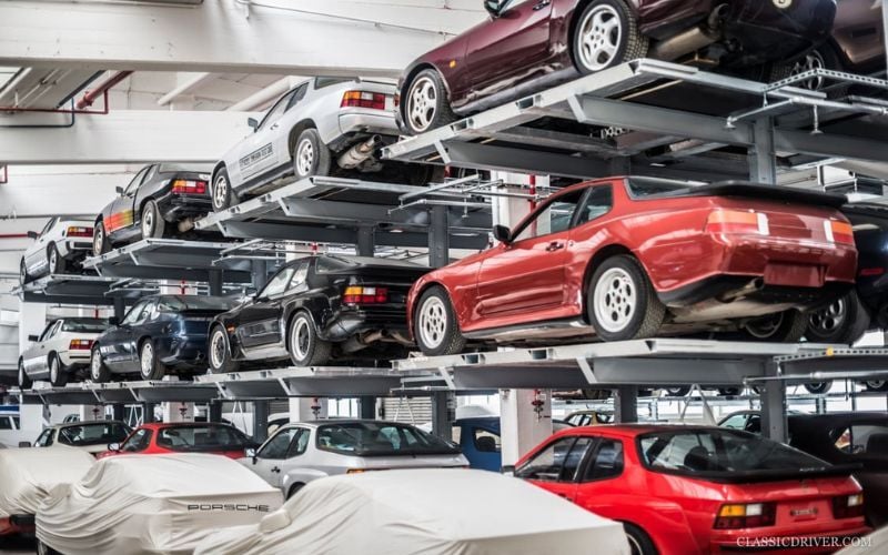 Multi-level car storage system with stacked classic Porsche vehicles in an indoor automotive warehouse