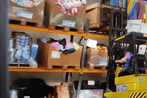 America Ferrera’s character hits the rack with her forklift without proper training, causing a rack collapse.