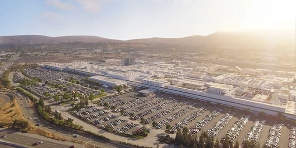Wide-angle view of Tesla’s Fremont Factory in California, showing the large manufacturing complex surrounded by roadways and parking lots.