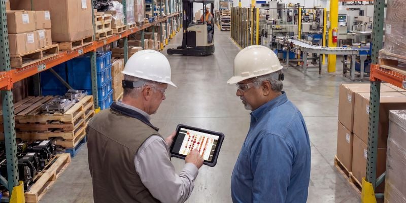 Gestionnaire d'entrepôt révisant les résultats d'inspection de palettiers avec un travailleur