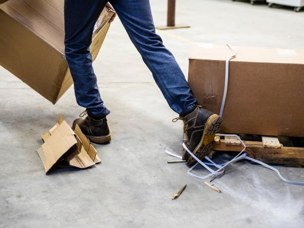 Warehouse worker trips on a box