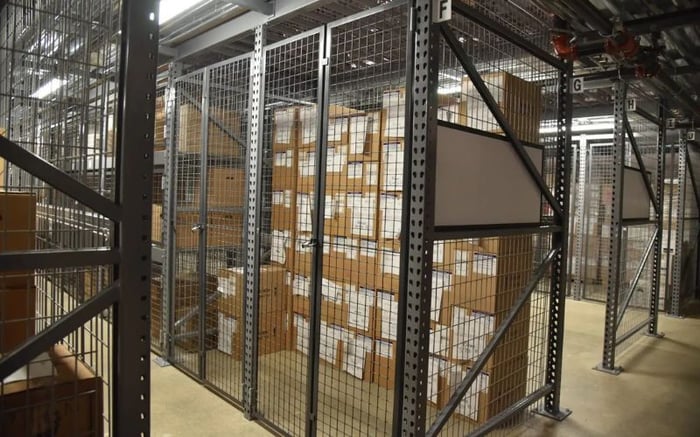 Secure wire mesh wine storage lockers inside a warehouse, designed to restrict access and maintain airflow for high-value or allocated wine inventory.