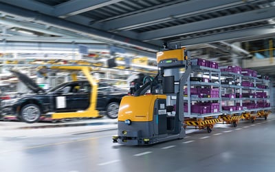 Automated guided vehicle (AGV) transporting parts through a BMW automotive assembly line in a modern manufacturing facility