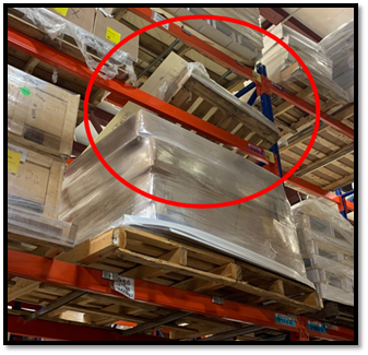 A pallet that has fallen between its supporting beams on a pallet rack.
